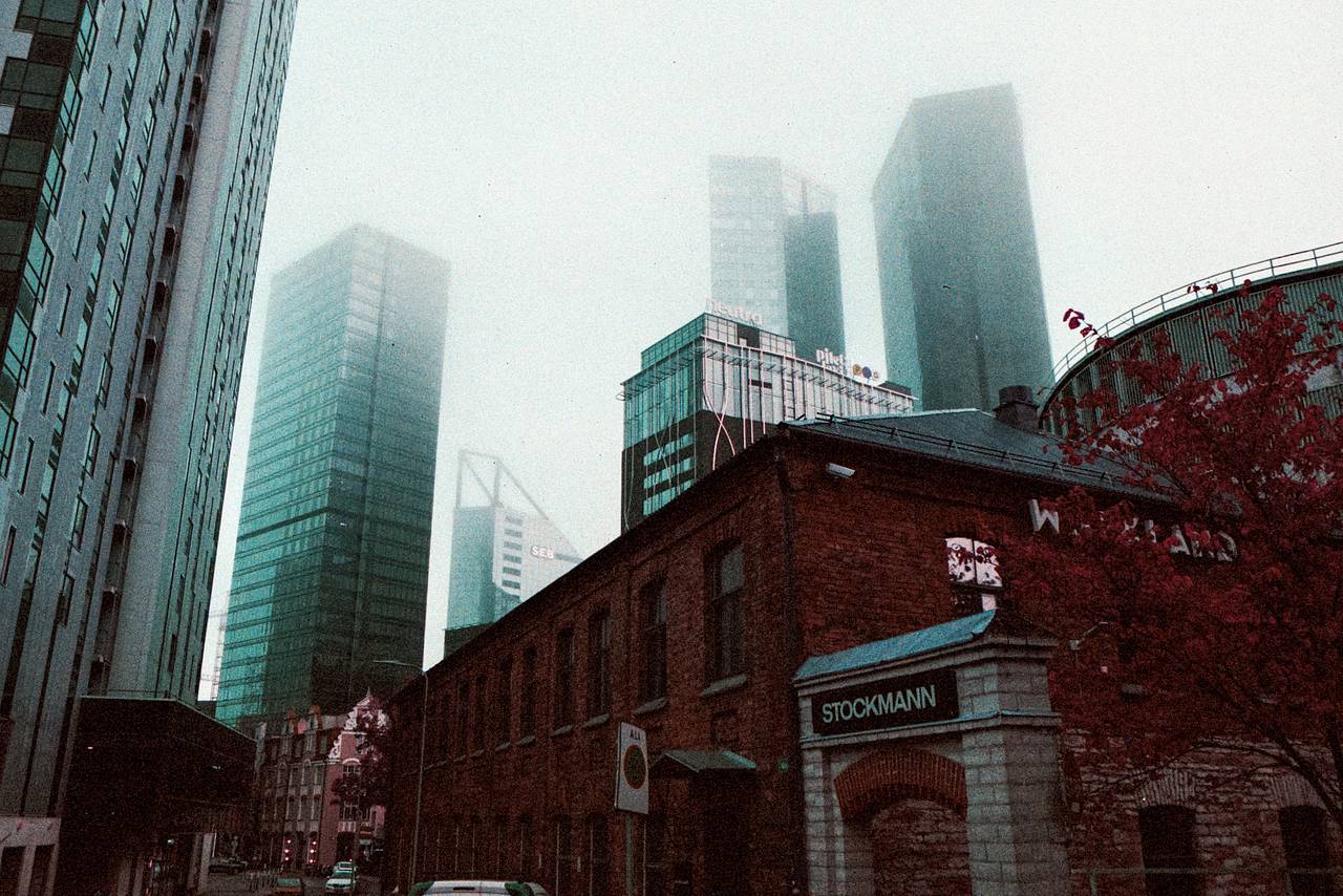 马克里区（Maakri Quarter）  是塔林垂直发展的核心地带。玻璃幕墙的高楼像镜子般切出明亮的峡谷，映出云层、有轨电车和几步之遥的老城剪影。走到街面上，可以找到快餐简餐、安静的写字楼大堂，还有那种属于工作日的沉静节奏。正午时分，光线从楼宇之间斜切而下；夜晚则亮起低调的微光。用 Lomo LC-Wide 广角胶片相机的超广角镜头，可以拍出那种强烈的比例感和几何阴影。(Photo by cerulionfrost)