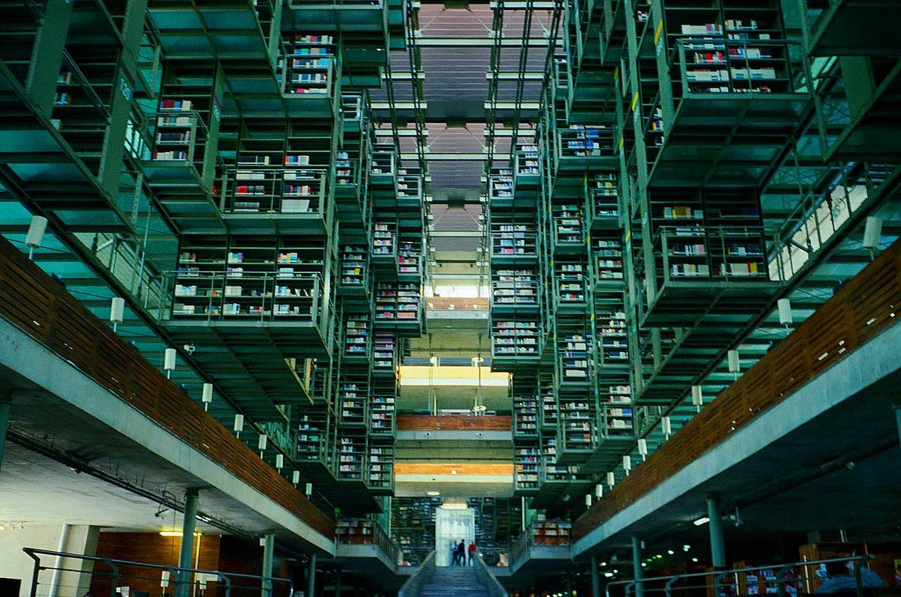 巴斯孔塞洛斯图书馆 （Biblioteca Vasconcelos） 坐落在墨西哥城的 布埃纳维斯塔 （Buenavista）  街区。这座震撼人心的建筑由建筑师阿尔贝托·卡拉奇（Alberto Kalach）设计，任何一位 Lomographer 见了都会惊叹不已，尤其是那些对建筑感兴趣的人。那些悬浮的书架，实际上是这座粗野主义风格建筑结构的一部分。你可以走到地面层，欣赏那几十万册藏书；也可以爬上几层楼，尝试各种不同的胶片角度。我们推荐你带上一台像 Lomo MC-A 这样的相机，它和这个空间一样，充满实验精神，颠覆又大胆。(Photo by filmphotocat)