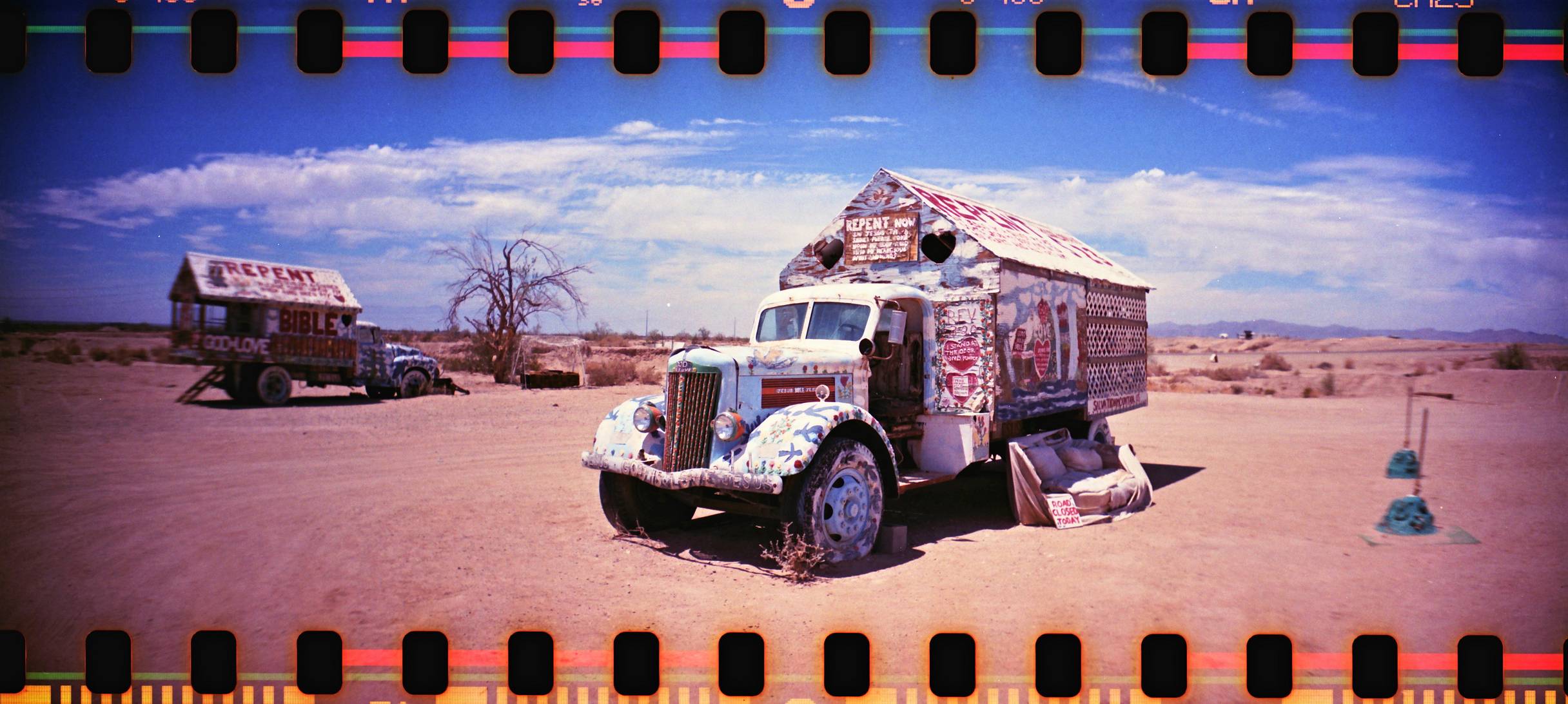 Two old trucks covered in foam and colorful paint in teh dessert