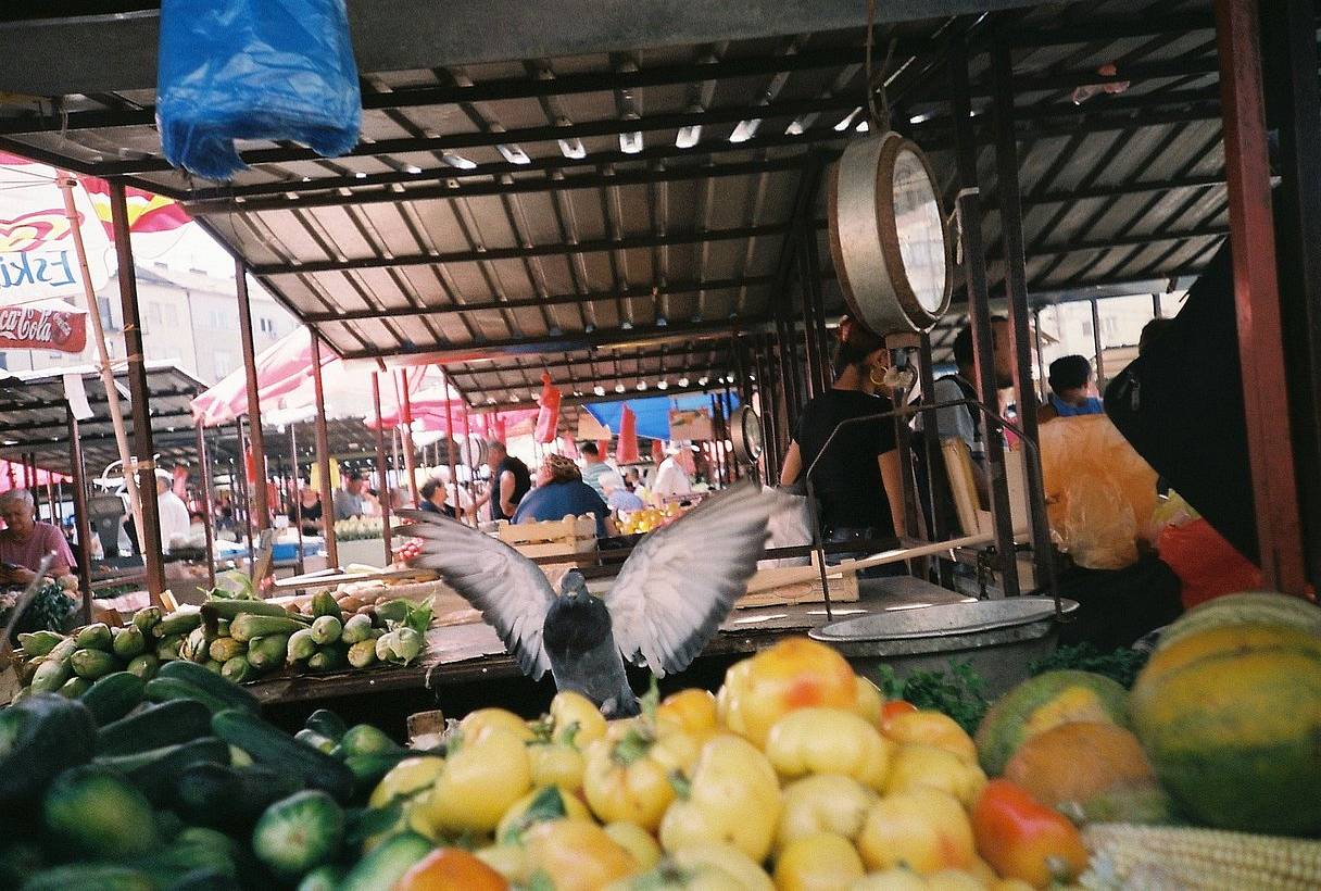 Kalenić Green Market 宛如城市中的村庄。除了堆满无花果、蜂蜜与日晒番茄的摊位，这里还蕴藏着静谧的诗意：瓦屋顶、手写价签，以及身着花围裙的商贩。对于早起者与 追逐自然光、柔和色调和永恒街景的胶片摄影师而言 ，这里无疑是一片天堂。(Photo by lazara )