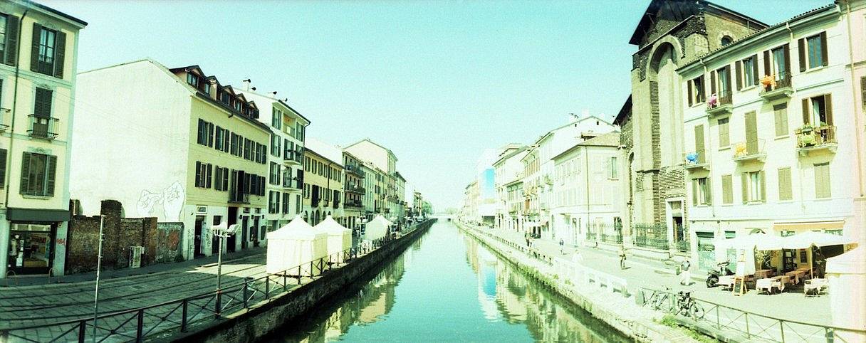 运河区（Navigli） 作为米兰最具代表性的街区之一，这里以波西米亚风情和迷人水景著称。运河两岸林立着咖啡馆与精品店，鹅卵石小道与彩色建筑相互衬托，是建筑摄影的绝佳取景地——特别是黄金时分的柔光，能让立面色彩更加饱满。入夜后，这里更化身长曝光创作的乐园：既可捕捉熙攘的酒吧人潮，也能拍摄水面倒映的静谧灯影。（Photo by tsingtao ）